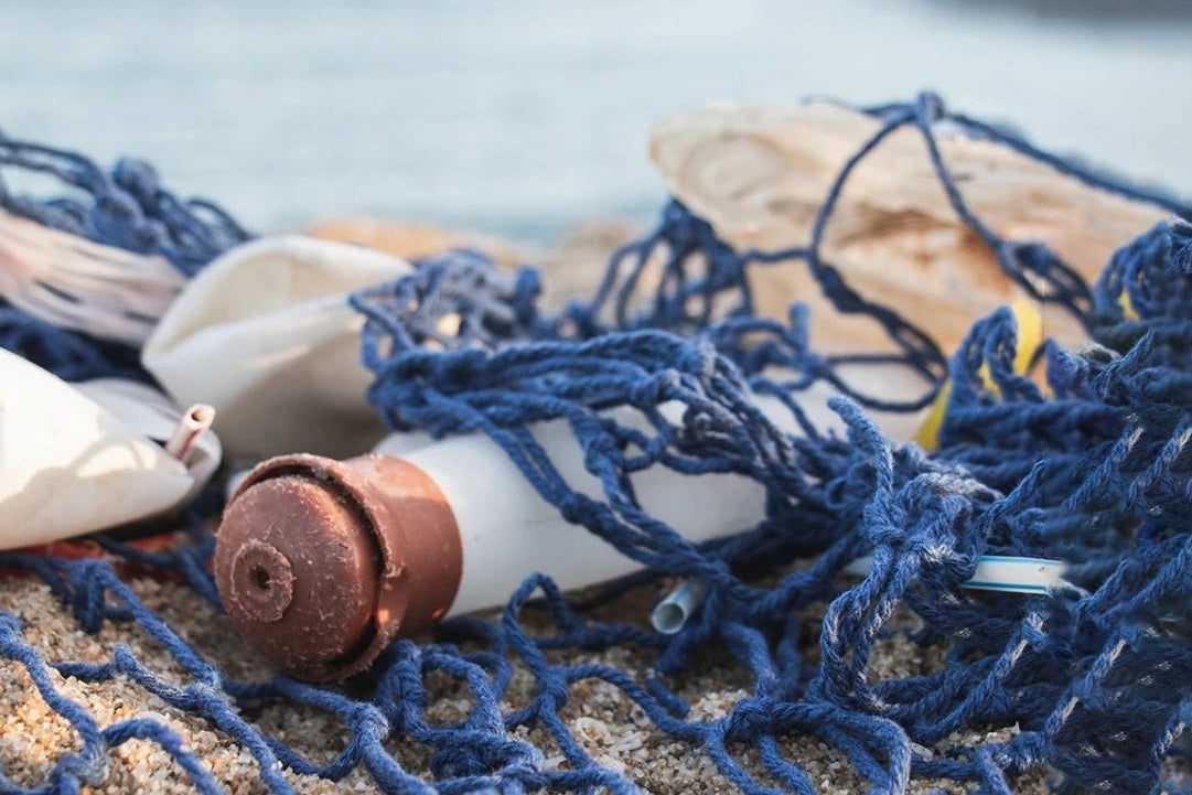 Two plstic bottles attached to a fishing net on a beach.