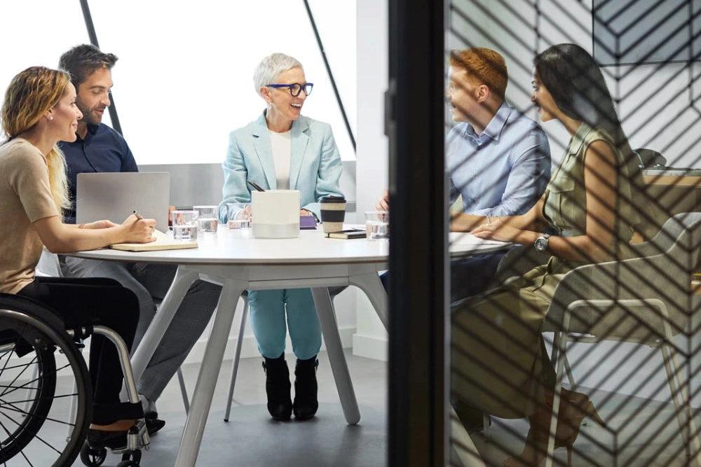 Group of people in a modern office setting around a conference table.