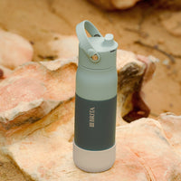 Green BRITA LARQ water bottle with beige silicone boot on a stone.