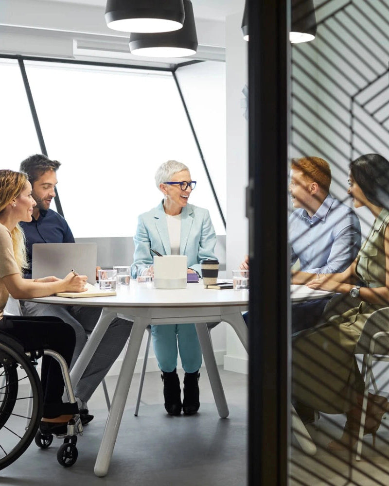Group of people in a modern office setting around a conference table.