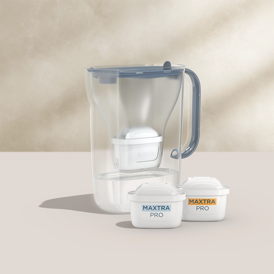 BRITA Style Essential in blue with two MAXTRA PRO filter cartridges on a beige background.