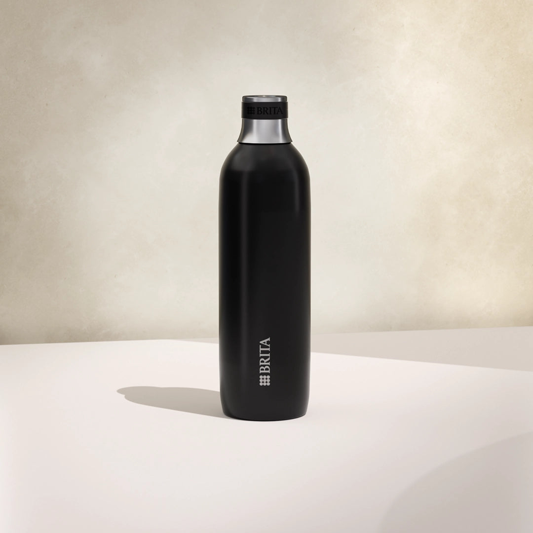 One large black BRITA sodaTRIO stainless steel bottle on a beige background