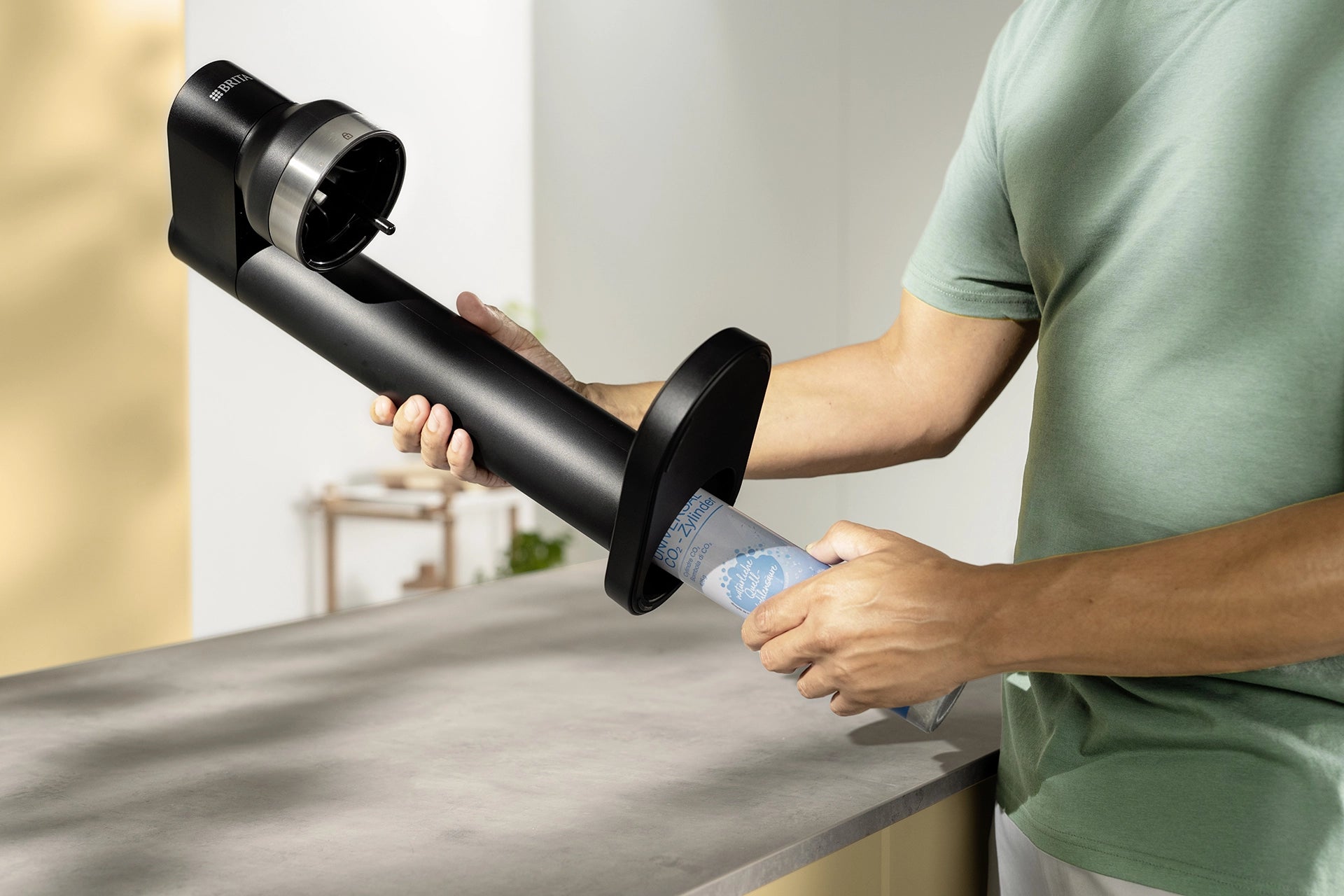 Person inserting a CO₂ cylinder into a black BRITA sodaTRIO Sparkling Water Maker.
