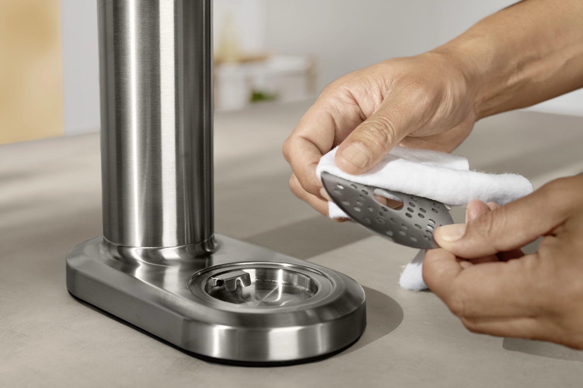 Person cleaning the drip tray of a BRITA sodaTRIO Pro Sparkling Water Maker with a cloth.