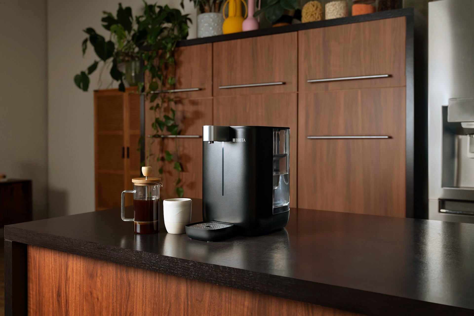 BRITA YOURCE mini water dispenser next to a coffee pot and a cup in a modern kitchen.